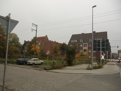 Farbfoto: Der beschrankte Bahnübergang über die Nesserlander Straße, die davor von der Nesserlander Straße nach links abzweigende Küstenbahnstraße und hinter der Bahnstrecke Emden-Leer die Fürbringerstraße. In Emden im Oktober des Jahres 2012. Foto: Erwin Thomasius.