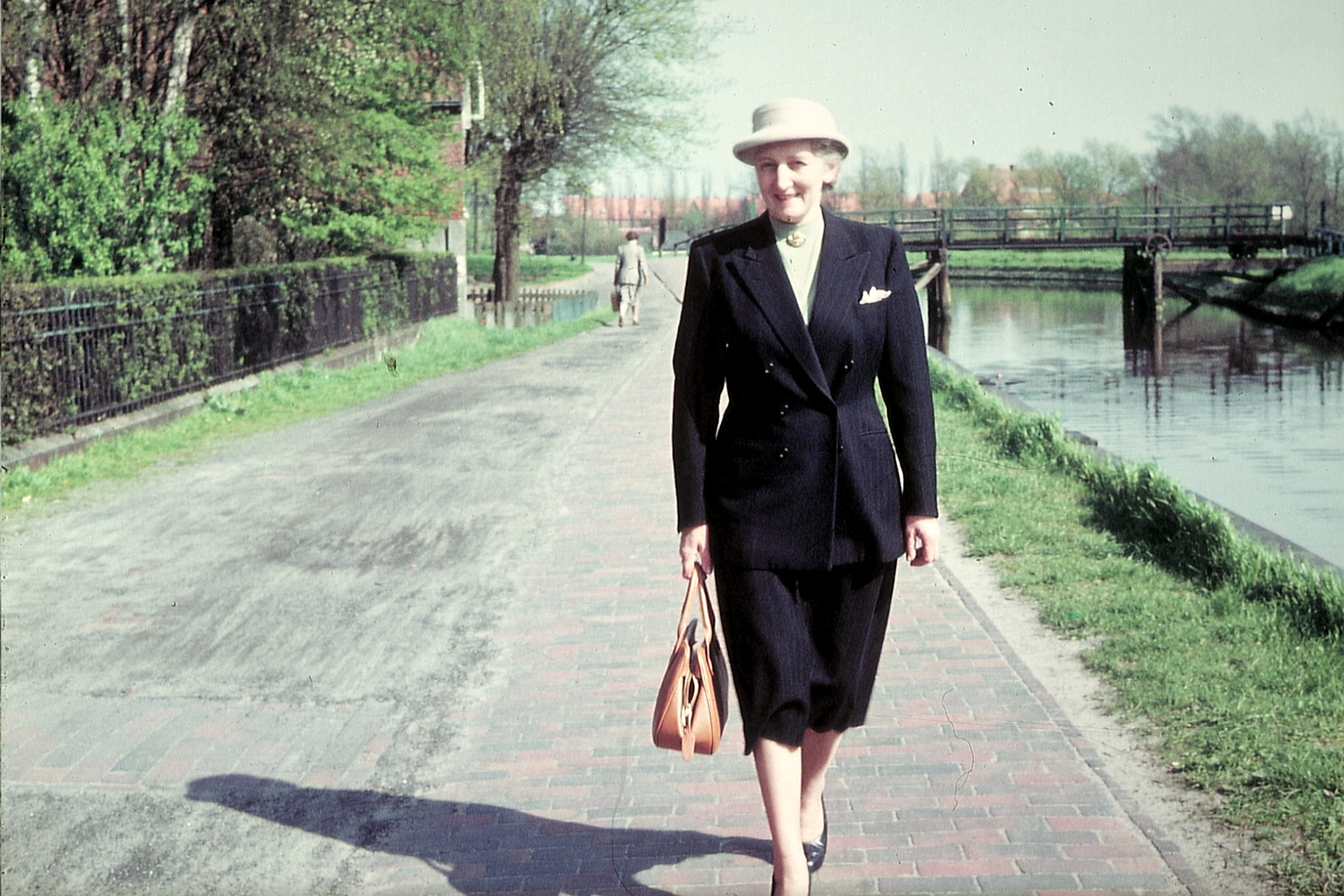 Farbfoto: Eine Emderin auf ihrem Weg von Kesselschleuse Richtung Innenstadt auf dem Weg Am Roten Siel. In Emden 1958. Foto: Ingrid Oostinga.