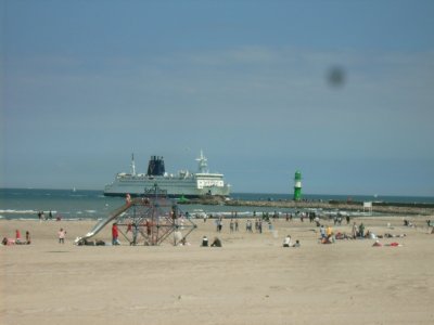 Farbphoto: Blick auf den Sandstrand in Warnemünde und auf eine  aus der Ostsee in den Hafen von Rostock hereinfahrende Skandinavienfähre. Juni 2009. Photograph: Bernd Paepcke.